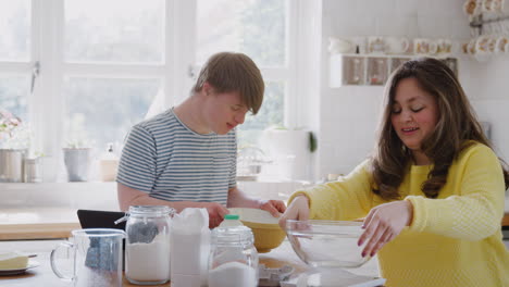 Young-Downs-Syndrome-Couple-Following-Recipe-On-Digital-Tablet-To-Bake-Cake-In-Kitchen-At-Home