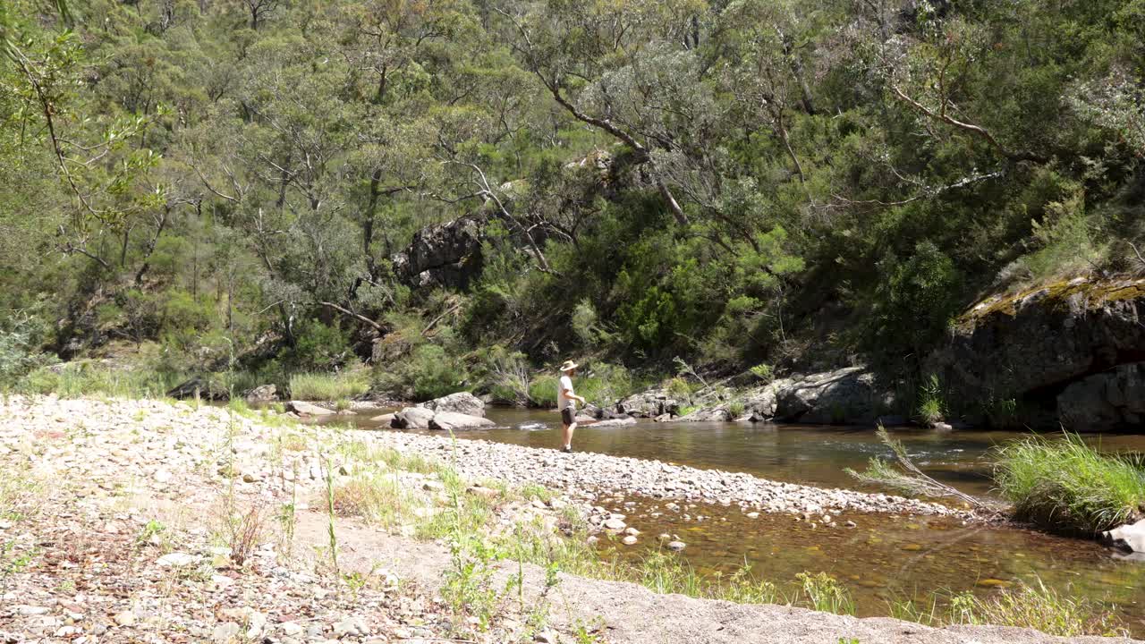 un pescador lanzando un señuelo en un hermoso río en el bosque australiano