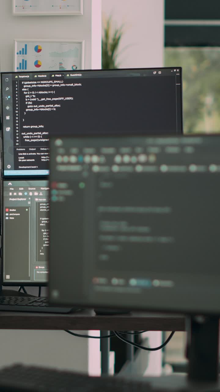 Vertical video: Computer screens on desk in empty data room displaying program code and