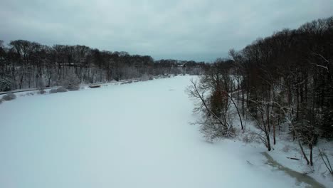 static shot of frozen creek in surrounded by forest and rocky mountains