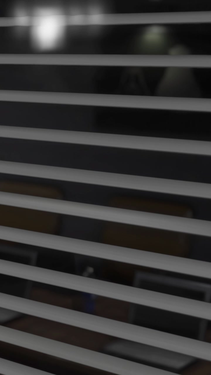 View through closed blinds at night with light shining from outside