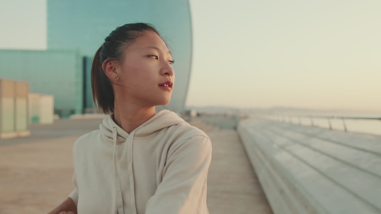パーカーを着たアジア人女性が海を眺めている。