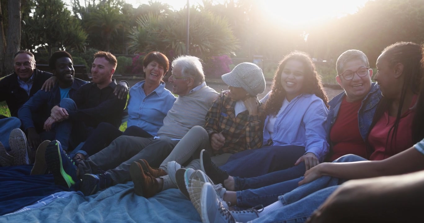 Happy Multi-Generational Friends Enjoying a Picnic in the Park at Sunset