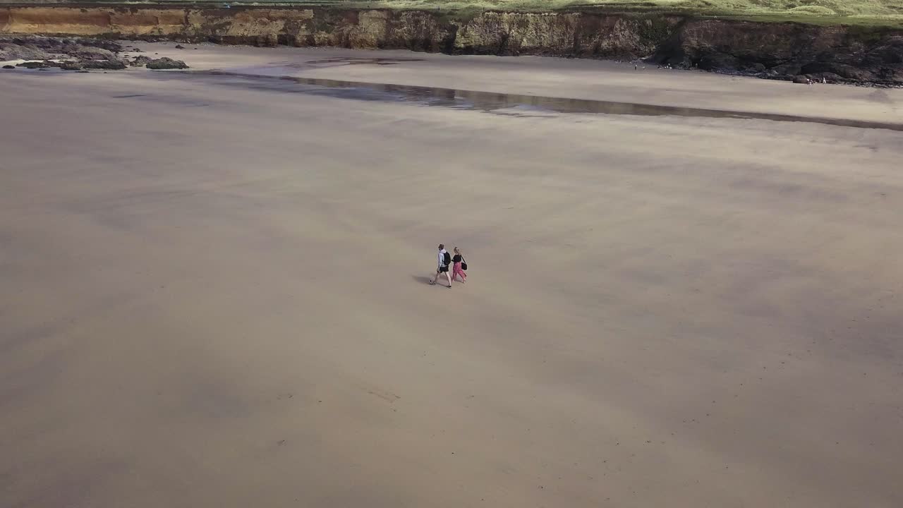 vista aérea de una pareja caminando en la tranquila orilla de la playa de godrevy en cornualles, inglaterra - disparo de drones