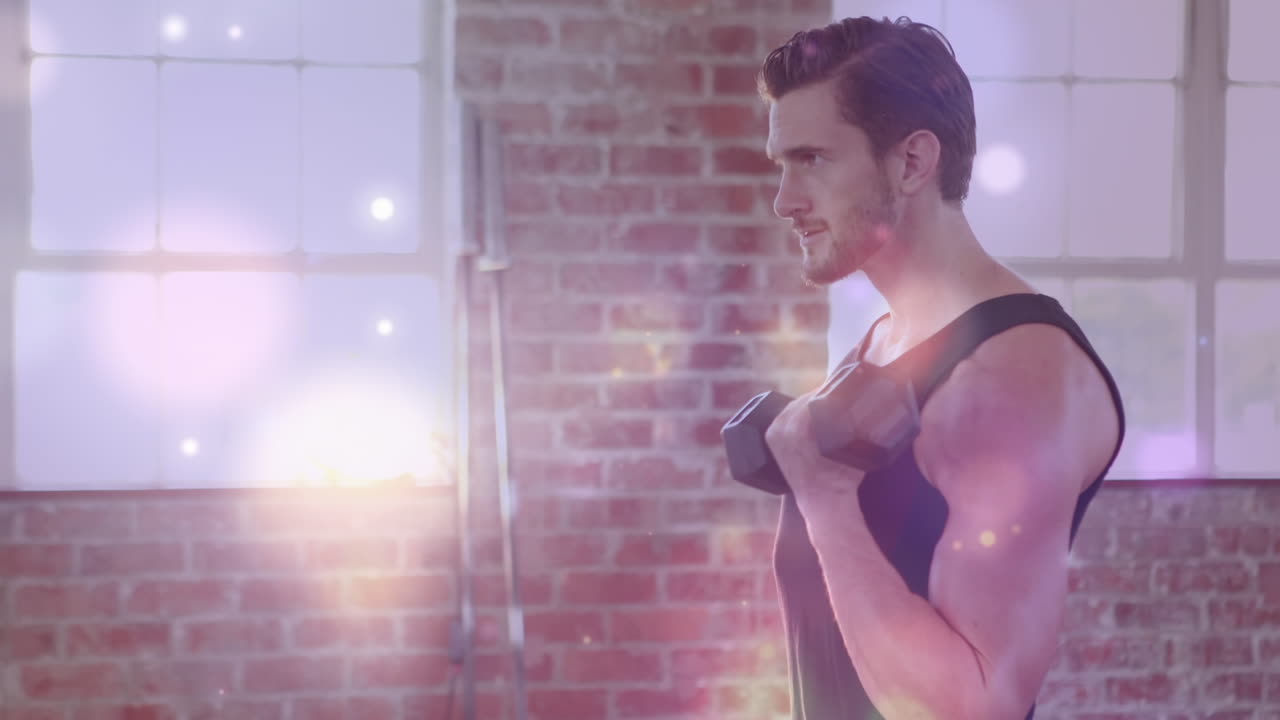 Animation of bokeh effect against caucasian young man building muscles with dumbbell in gym