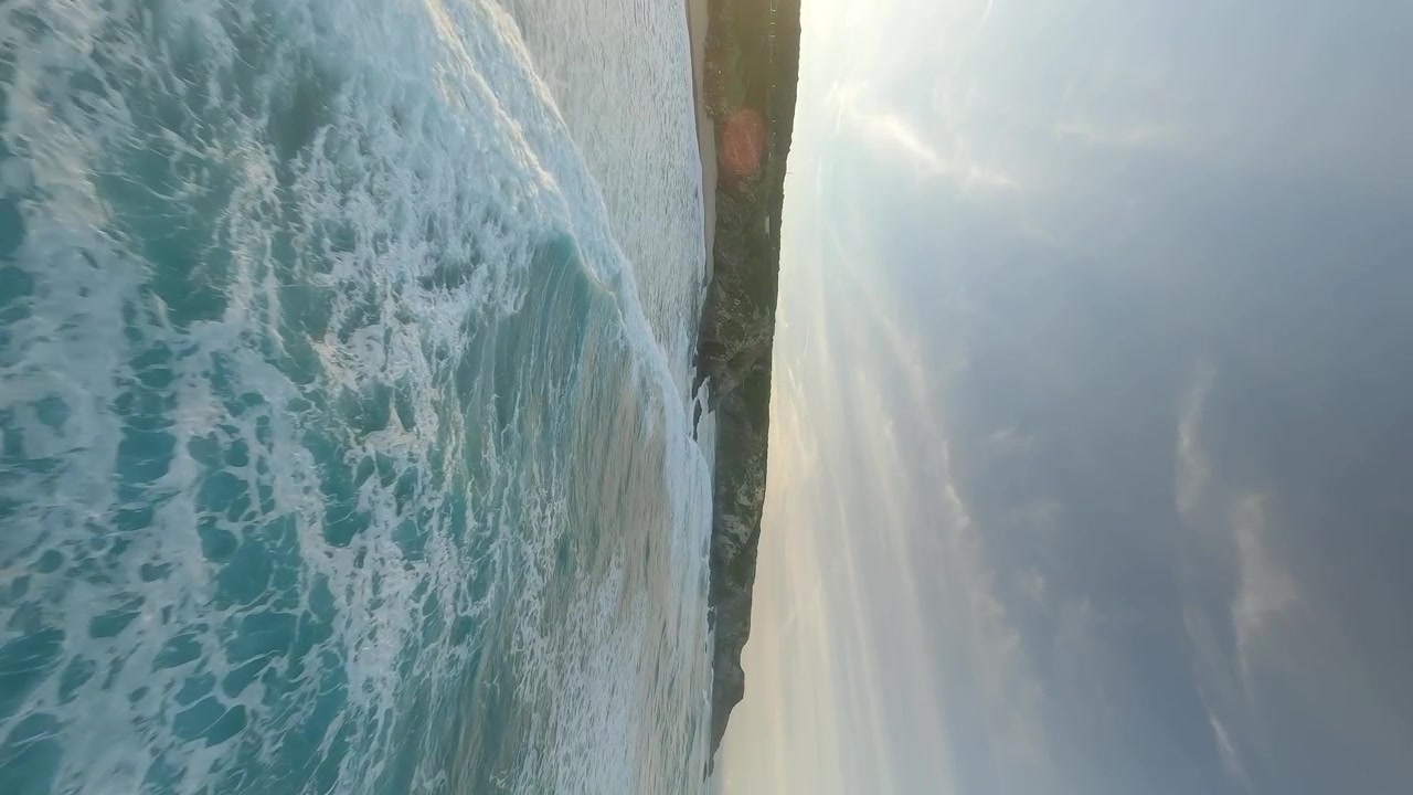 Drone FPV a bassa quota che vola ad alta velocità sopra le onde che si infrangono su una spiaggia remota in Algarve, Portogallo.