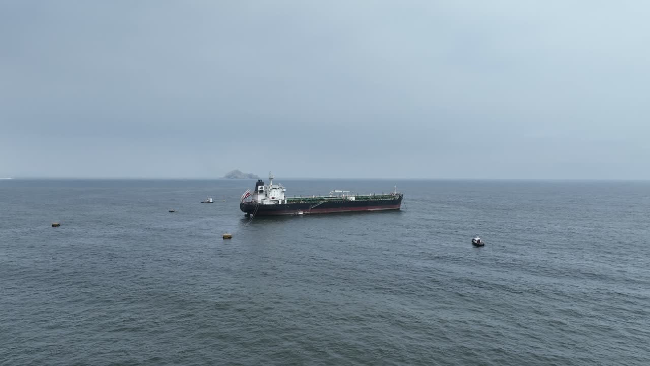 백그라운드에서 섬에서 언덕의 전망과 함께 태평양에 떠있는 작은 보트와 대형 화물선의 공중 앞으로 돌리 샷