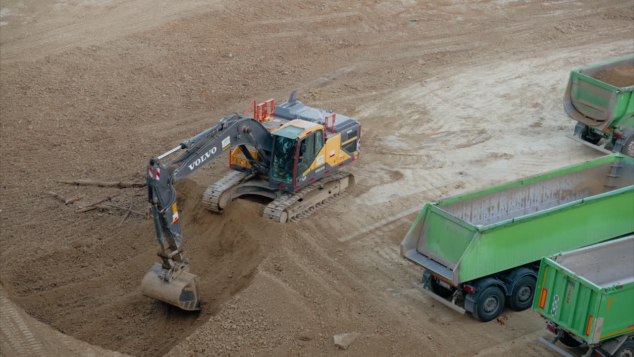 Excavator Filling and Arranging Dirt on Green Dump Truck, Preparing the material for transport on an active construction site. Groundwork and excavation work on a construction site.