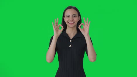 anfitriona de noticias india feliz mostrando una pantalla verde con un letrero de acuerdo