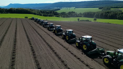 a long line of tractors preparing a field for planting