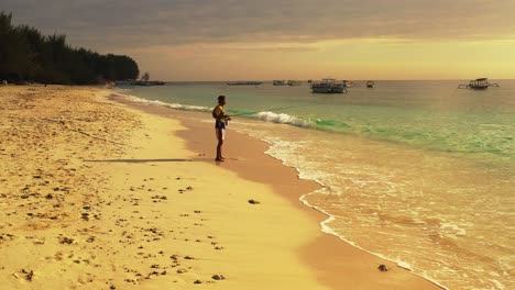 hombre joven en forma pescando en las olas del océano de una isla de playa tropical durante la tarde