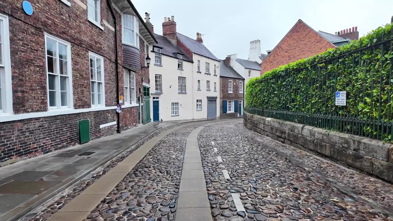 Brostensbelagt gade i Durham, England, med gamle bygninger og stenbelægning