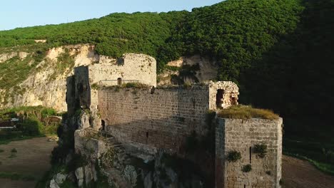 dolly in to historical mseilha fort around green mountain ranges, aerial clip lebanon