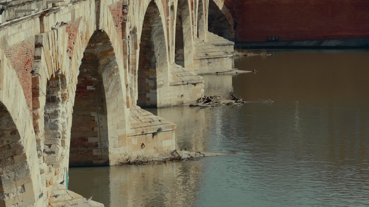 Historyczny kamienny most łukowy nad spokojną rzeką