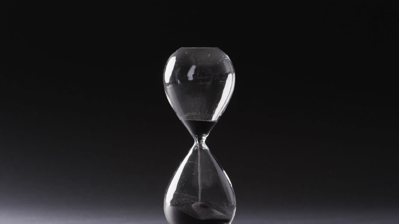Video of hourglass with sand pouring, copy space on black background