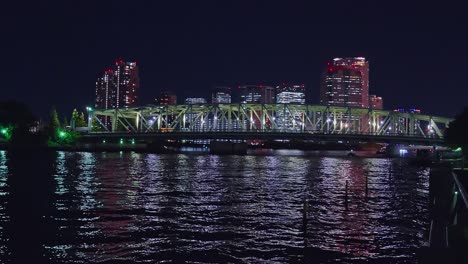 Luz-Nocturna-Tokio,-Tsukuda,-Rascacielos-Toyosu-Y-Puente-Sobre-El-Río-Sumida-Yakatabune,-Embarcación-De-Recreo