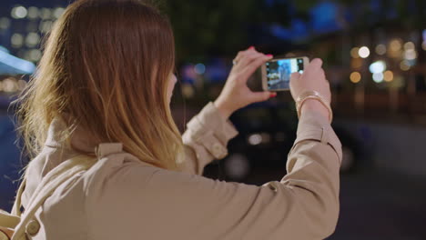 close up portrait of pretty blonde woman tourist taking photo with smartphone enjoying calm urban evening