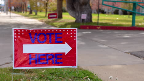 Vote-Here-Signs-Pointing-Right-In-Front-Of-Empty-Road,-Close-Up