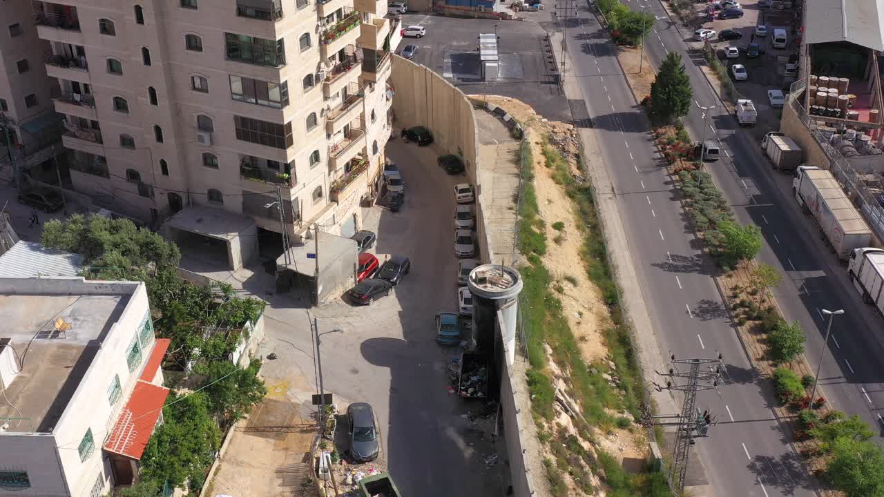 Aerial view of a city road with a security barrier, buildings, and traffic
