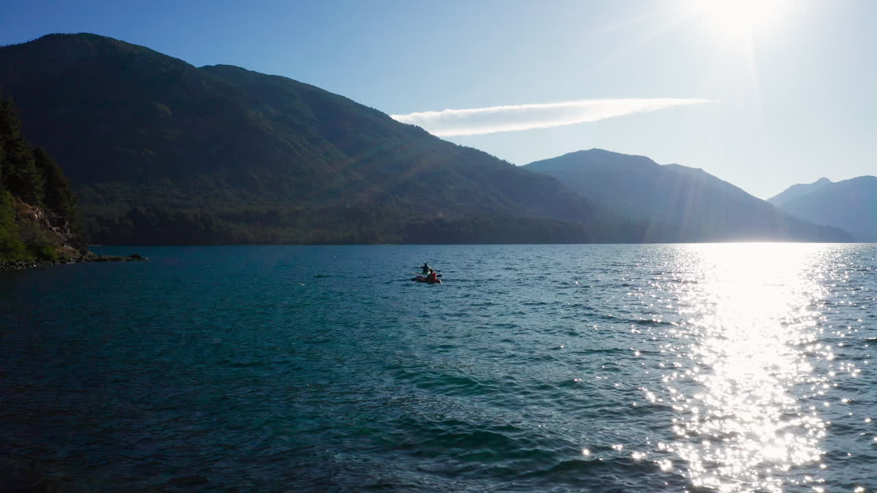 Two kayaks paddled on wavy lake water by Andes mountains, static view
