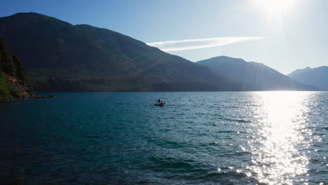 Dos-Kayaks-Remando-En-El-Agua-Del-Lago-Ondulado-Por-Las-Montañas-De-Los-Andes,-Vista-Estática