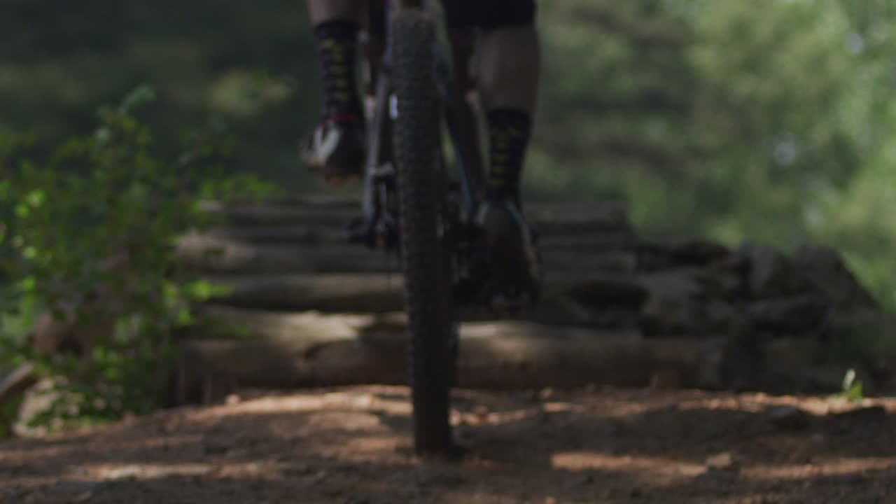 Man riding a mountain bike in the forest, slow motion close-up of pedals