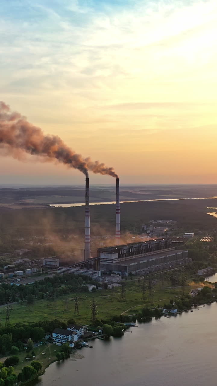 View from above the countryside near the river in the evening. Orange sun reflection in the water at beautiful rural background in summer at sunset. Camera moves right. Vertical video