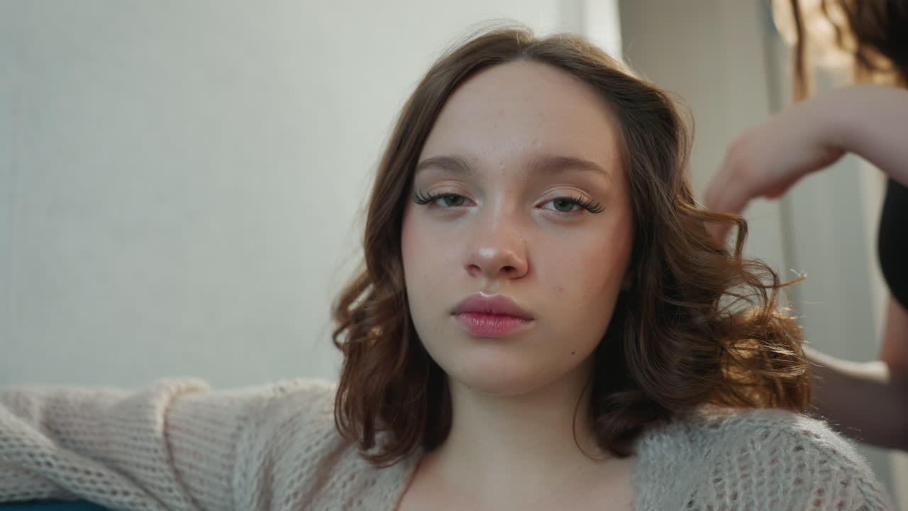Woman Reclining During Hair Styling, Female With Styled Hair Lounges Comfortably In Salon Setting, Young Woman With Elegant Hairstyle Sits Relaxed On Sofa During Beauty Treatment Session