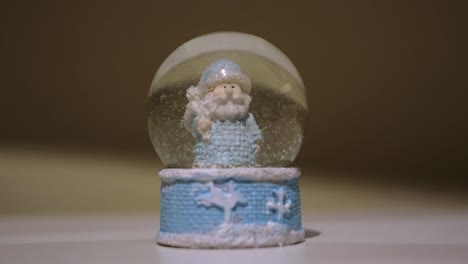 bola mágica de navidad con el padre frost. concepto. primer plano de un símbolo de año nuevo - bola de vidrio con nieve cayendo en el interior, recuerdo de pie en la superficie blanca de la mesa.