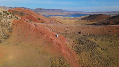 furgoneta a lo lejos escalando una carretera 4x4 con un lago al fondo