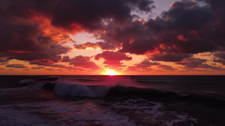 Dramatic sunset over ocean waves with vibrant red sky