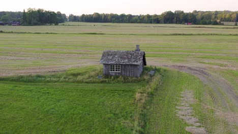 weathered wooden structure of an old swedish blacksmith workshop standing alone on field. aerial shot