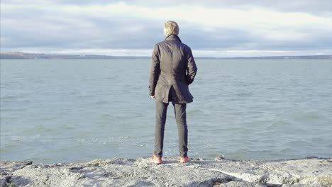 man contemplating at the lakeside