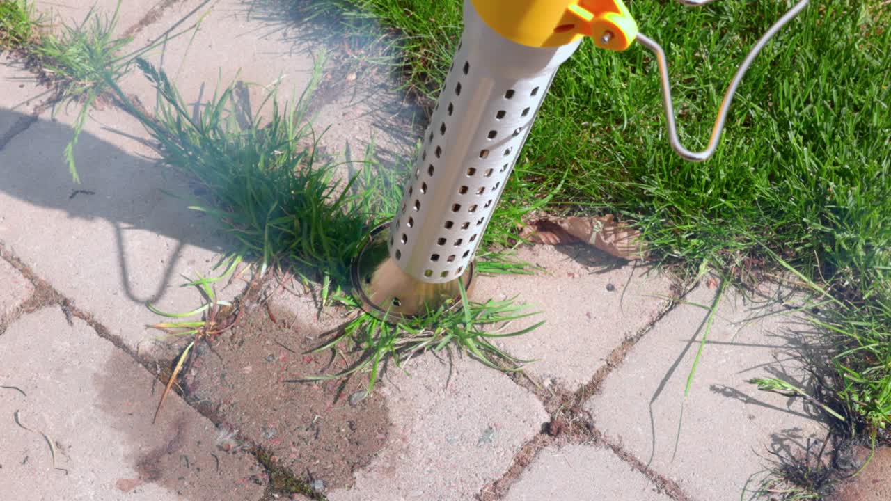 Short film showing process of burning grass between street tiles with an electric burner. Sweden.