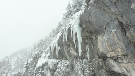 low angle dolly of large icicles hanging of mountain ridge