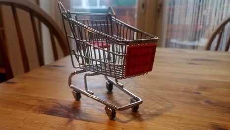mini carrito de compras vacío concepto de entrega a domicilio en línea en la mesa de la cocina tire hacia atrás para revelar ampliamente