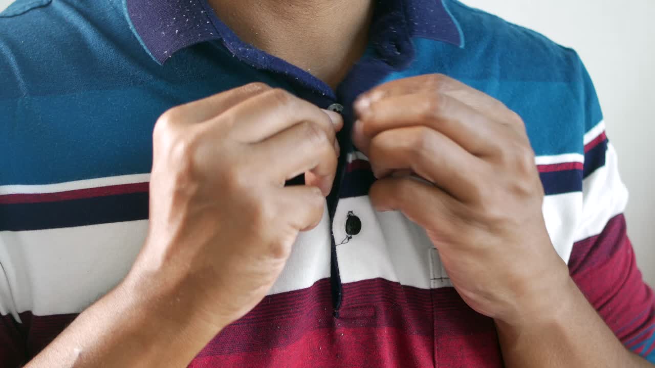 un hombre abotonando una camiseta de polo.