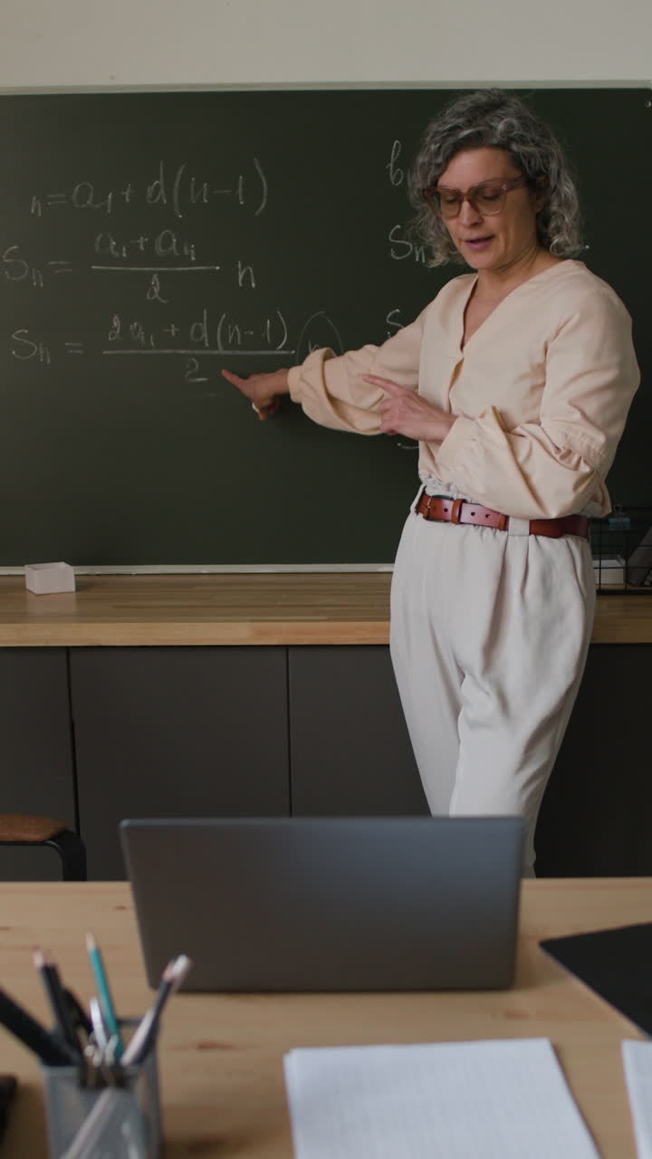Teacher Explaining Math Equations on a Blackboard