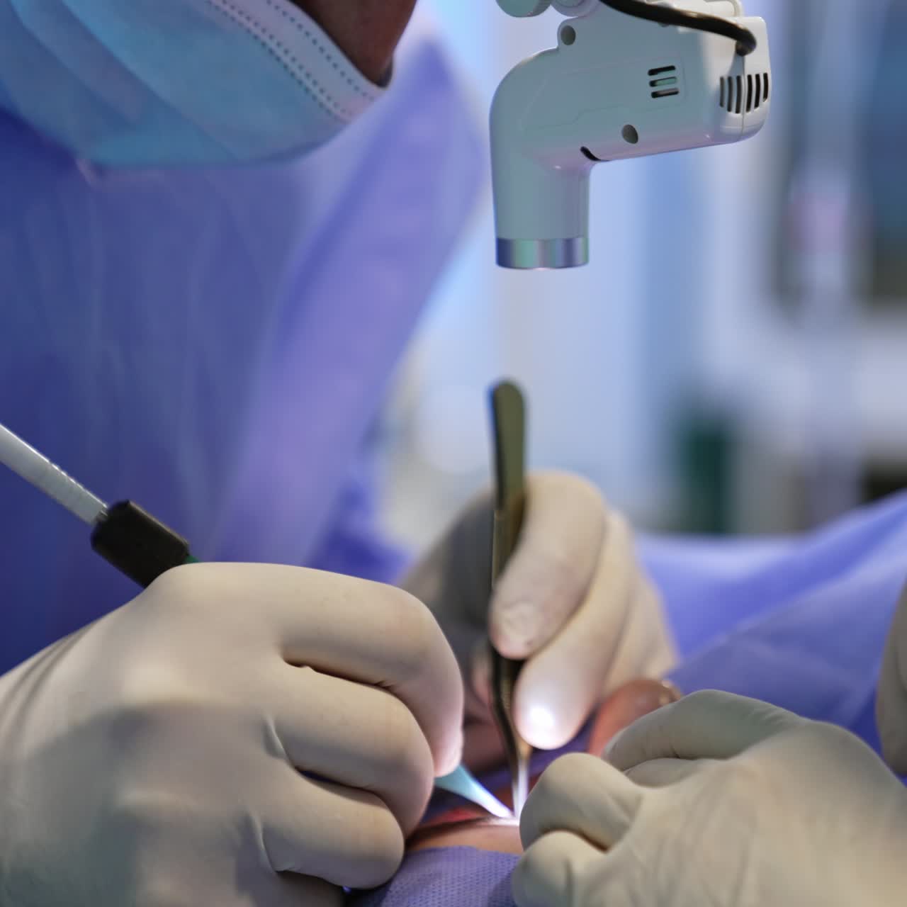 Doctor with headlight on head uses metal tool and electric device in surgery. Eyelid operation close up