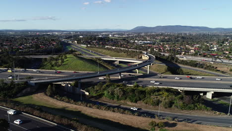 slow drone tracking and sliding around major highway interchange above suburb sprawl below