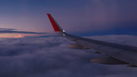 view from airplane window and the wing with sunrise sky over clouds