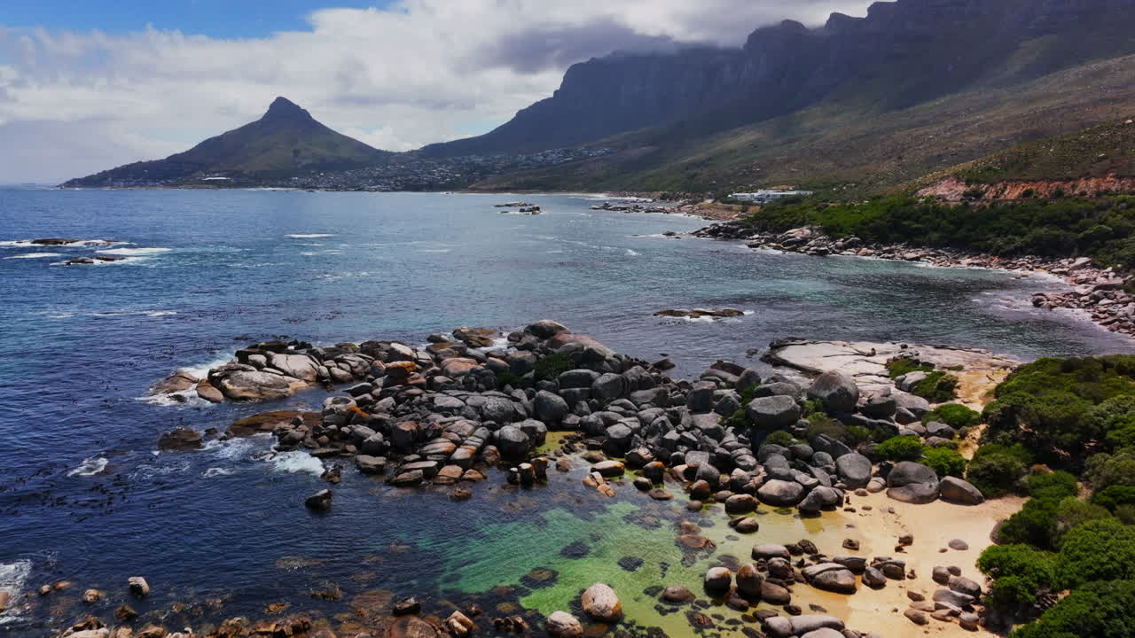South African stunning summer beach Hommetjie Bakoven Beach view of Table Mountain Lion's Head drone aerial cinematic rugged boulder coastline white sand deep aqua blue ocean sea forward pan up motion