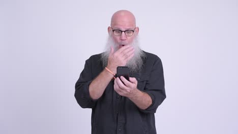 mature bald bearded man using phone