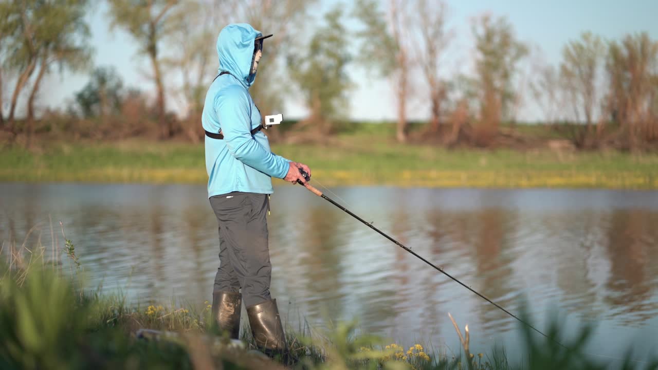 어부 스포츠맨은 호수에서 회전하는 포식자 물고기를 잡습니다.