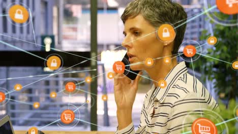 Animation-of-network-of-connections-with-icons-over-caucasian-businesswoman-talking-on-smartphone