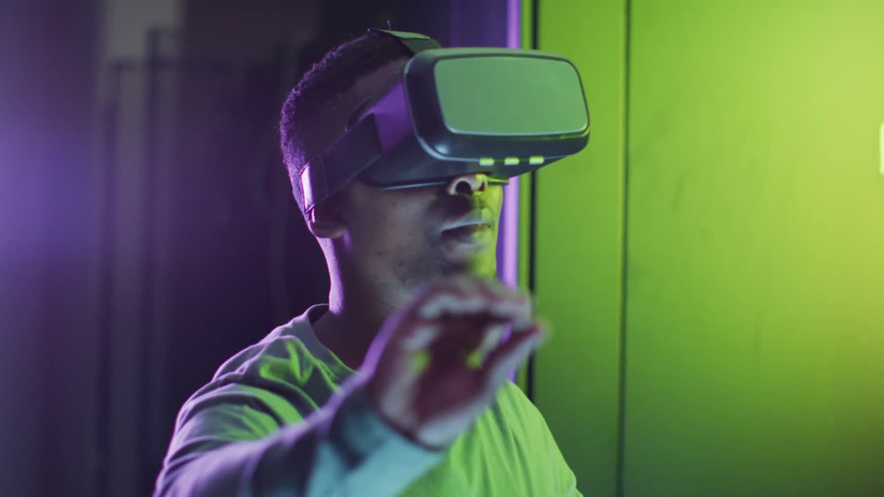 tecnico informatico maschio afroamericano che usa le cuffie vr che lavora in una sala server aziendale