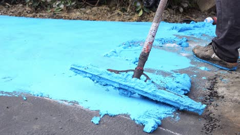 construction worker spreading blue asphalt on a road