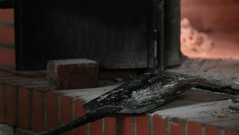 baker put the dough inside the brick oven using a metal peel with long wooden handle