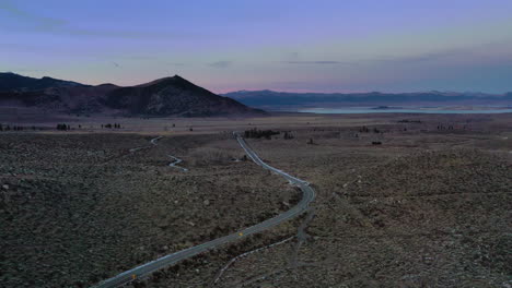 Wunderschöne-Landstraße-Durch-Verlassenes-Gebiet-Mit-Kleinem-Berg-Am-Horizont,-Drohnenansicht-Aus-Einem-Hohen-Winkel