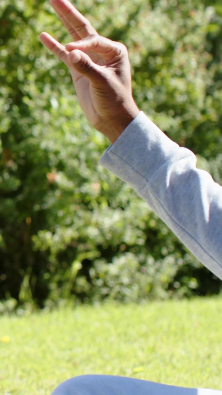 Vertical video: Turning head, man in hoodie, purple tee reaching arm gesturing at park, copy space